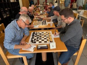 Zwei Spieler am Brett, Partieformular und Schachuhr daneben